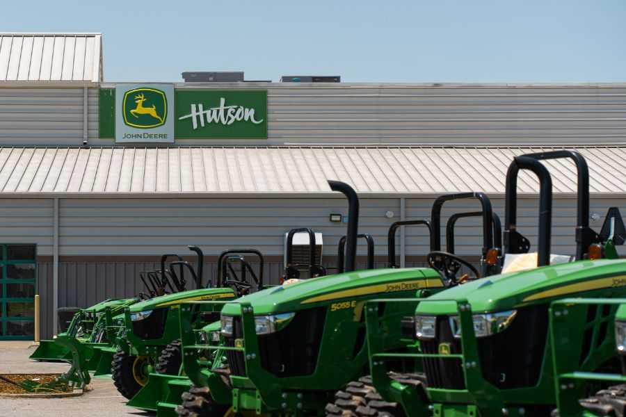 John Deere tractors lined up in the lot with the Hutson John Deere sign in the background.