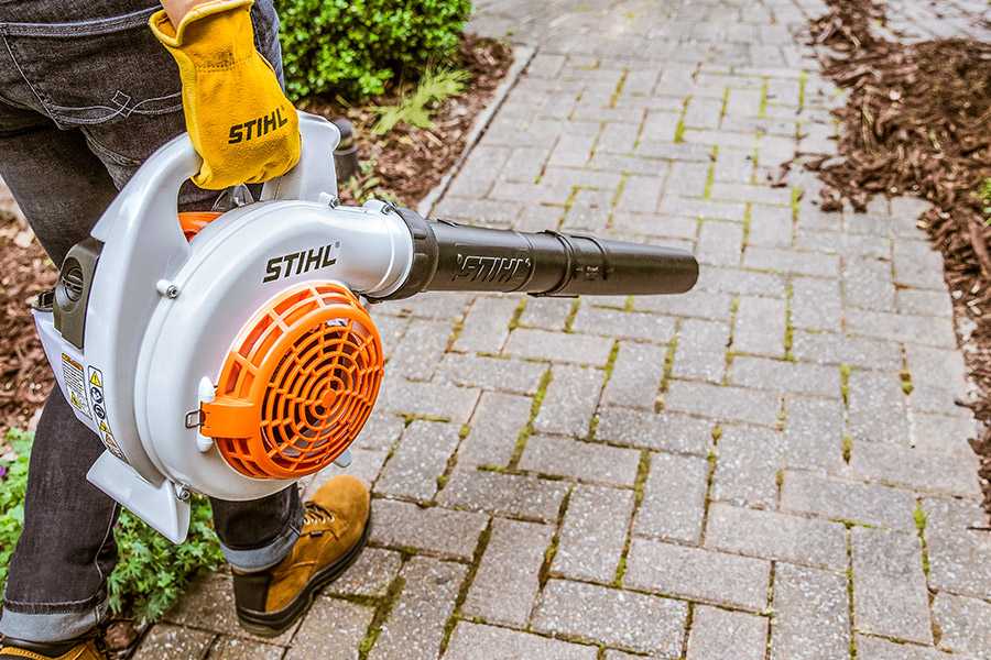 Person using a STIHL BG 56 blower to clear leaves from a walkway